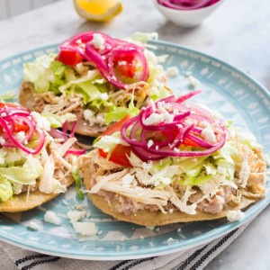 Tostadas de Pollo 
 Crisp corn tortillas crowned with shredded, spice-kissed chicken, fresh lettuce, and thinly sliced radishes, finished with a drizzle of light crema.